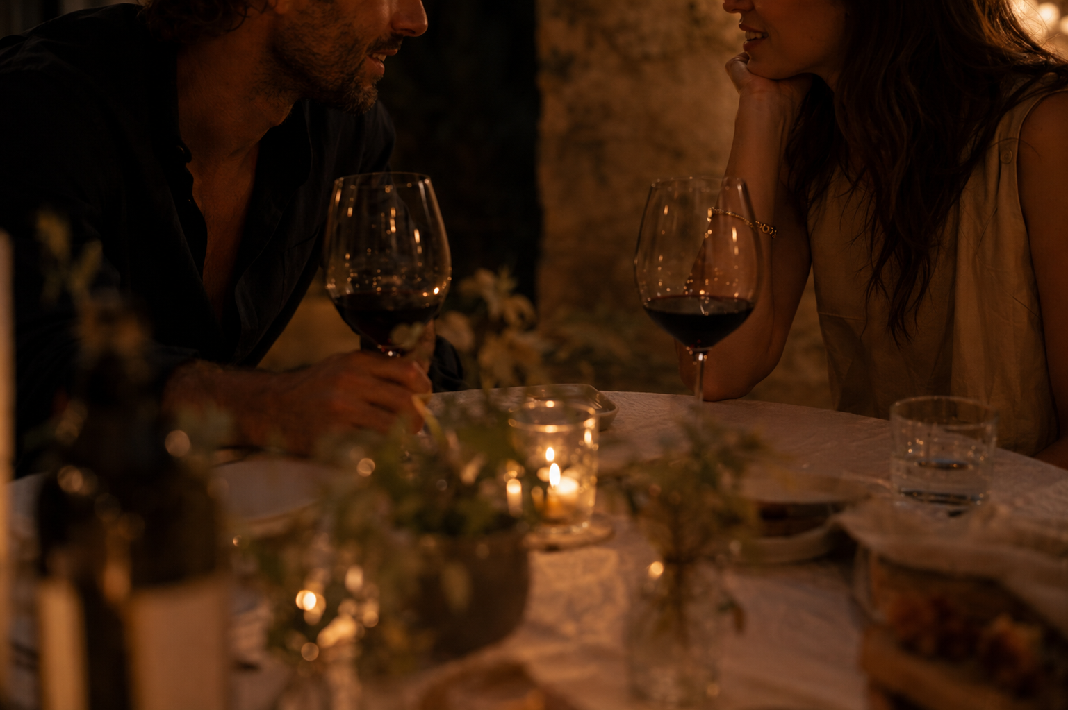 Two people in close conversation over wine by candlelight